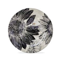 a black and white plate with sunflowers painted on the side, in front of a white background