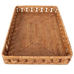 a brown wicker tray with handles and decorative designs on the sides, isolated against a white background