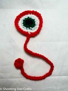 a crocheted red and white object with a green center on it's end