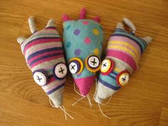 three colorful stuffed animals sitting on top of a wooden floor