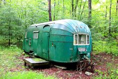 an old trailer is sitting in the woods