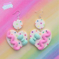 two heart shaped earrings with pink, blue and green bowknots on them