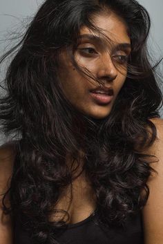 a woman with long dark hair is posing for the camera