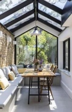 an enclosed patio area with couches, tables and windows on the side of it