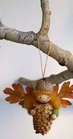 an ornament hanging from a tree branch with leaves and acorns on it