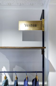 clothes are hanging on the rail in front of a sign that says vestes and two coats hang from them