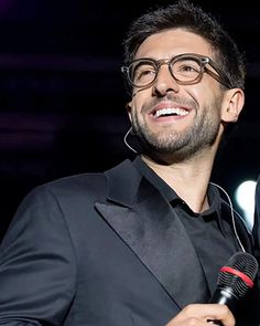 a man wearing glasses and holding a microphone