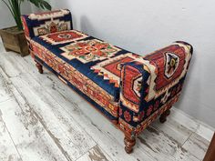 a colorful bench sitting on top of a wooden floor next to a potted plant