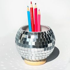 several colored pencils sticking out of a silver disco ball