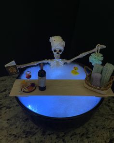 a skeleton sitting on top of a table next to a bottle of wine and candles