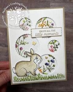 a hand holding up a card with an image of a bunny and flowers on it