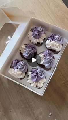 a box filled with cupcakes sitting on top of a wooden table