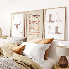 a bed topped with pillows and blankets next to two framed pictures on the wall above it