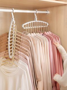 a woman looking at clothes on hangers in a closet