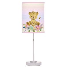 a lamp with a teddy bear on it's side and flowers around the base