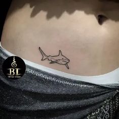 a woman's stomach with a small shark tattoo on it