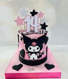 a pink and black birthday cake with an adorable kitty figure on the top, surrounded by stars