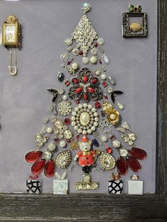 a christmas tree made out of buttons and other items in a shadow box with a clock on the wall behind it