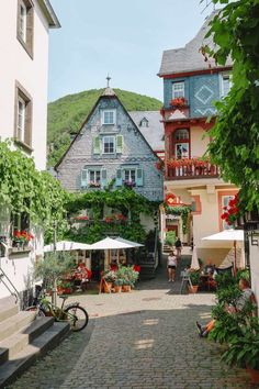 a cobblestone street lined with buildings and umbrellas in the middle of town