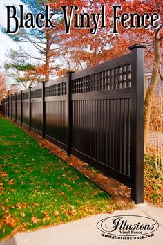 a black vinyl fence in the fall with leaves on the grass and trees behind it