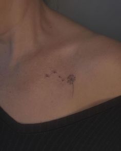 a woman's chest with a dandelion tattoo on the left side of her neck