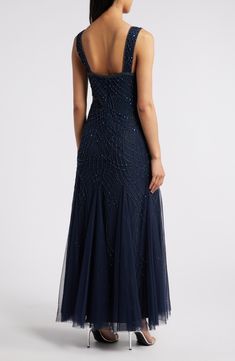 a woman in a dark blue evening gown with sequins on the back and straps