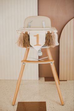 a baby high chair with a number one on the front and fringed seat cover