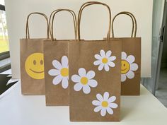 three brown bags with white daisies and smiley faces on them