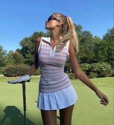 a woman standing on top of a green field holding a golf club