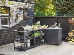 an outdoor bbq grill with lots of vegetables on the table and in front of it