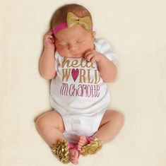 a newborn baby wearing a white shirt and gold headband