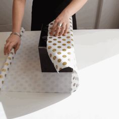 a woman is wrapping a box with polka dots