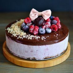 a chocolate cake with berries and other toppings on a wooden platter, ready to be eaten