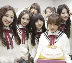 a group of young women standing next to each other with a cake in front of them