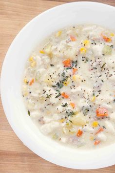 a white bowl filled with fish chowder on top of a wooden table