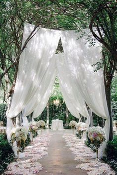 an image of a wedding ceremony with flowers and white draping on the aisle