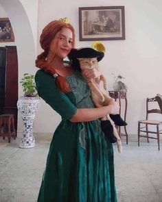 a woman in a green dress holding a cat