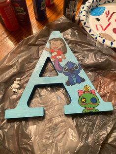 a wooden letter with cartoon characters on it sitting on aluminum foil next to some other items