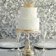 a three tiered wedding cake on a table with silver plates and wine glasses next to it