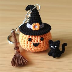 a crocheted pumpkin keychain with a black cat sitting on it's side