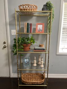 a shelf with books, plants and pictures on it