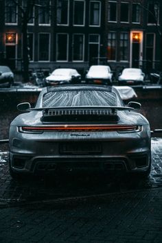 the back end of a car parked in front of a building on a rainy day