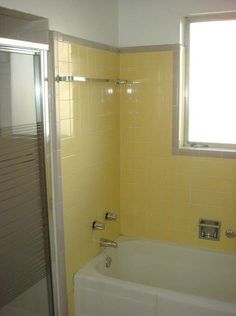 a bath tub sitting under a window next to a shower head mounted faucet