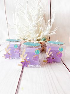 three purple boxes with blue and gold designs on them sitting next to a white tree