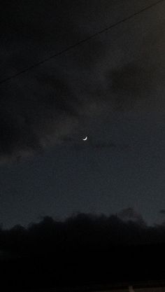 the moon is seen in the dark sky above some power lines and telephone wires at night