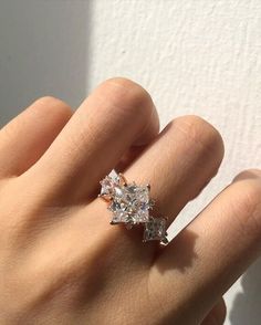 a woman's hand with a diamond ring on top of her left hand,