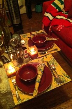 a table set for two with candles and place settings on the plates in front of them