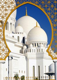 an ornate white building with gold trim around the top and bottom dome, viewed through a golden frame