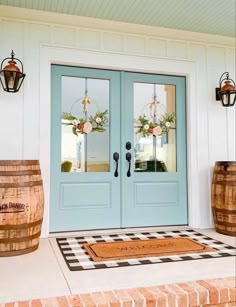 two wooden barrels sitting on the side of a building next to a blue front door