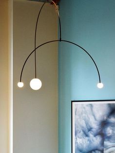 three lights hanging from the ceiling in a room with blue walls and artwork on the wall